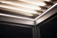 Podświetlenie ukryte w konstrukcji pergoli Tarasola Essential rozjaśnia wieczorne przestrzenie tarasu, tworząc przytulny klimat pod lamelowym dachem. Minimalistyczna forma aluminiowych profili subtelnie kontrastuje z ciemnym niebem, a otaczająca zieleń dodaje całości naturalnej harmonii.