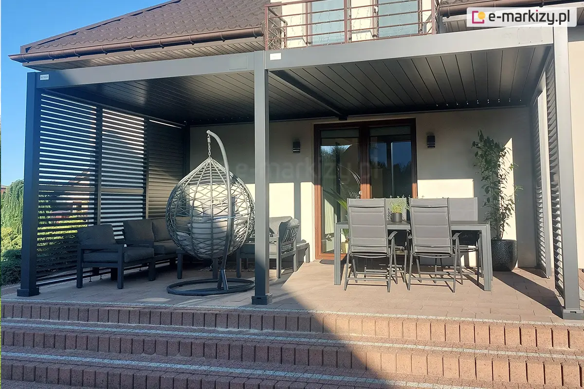 Antracytowa pergola przyścienna Rubio z otwieranym dachem lamelowym i żaluzjami bocznymi, zadaszająca strefę wypoczynkową na tarasie.