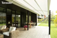 Tarasola Light zadaszenie tarasu z tkaniny Opatex w kolorze białym, rozwijany wodoodporny dach przeciwsłoneczny nad drewnianym tarasem przy nowoczesnym domu, minimalistyczna pergola przyścienna z aluminiową konstrukcją i jednospadowym dachem zwijanym.